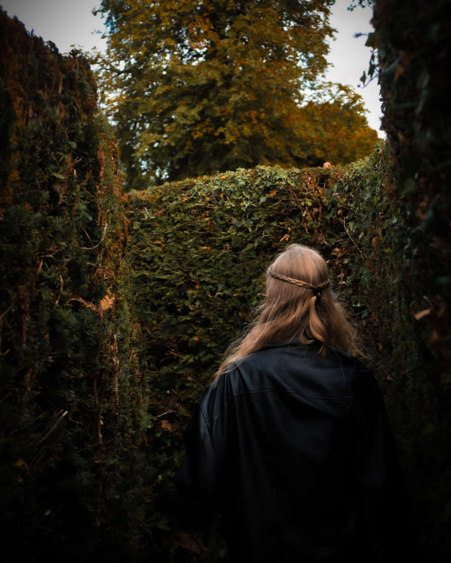 Artistic portrait of woman walking through trimmed hedges – Haslemere setting
