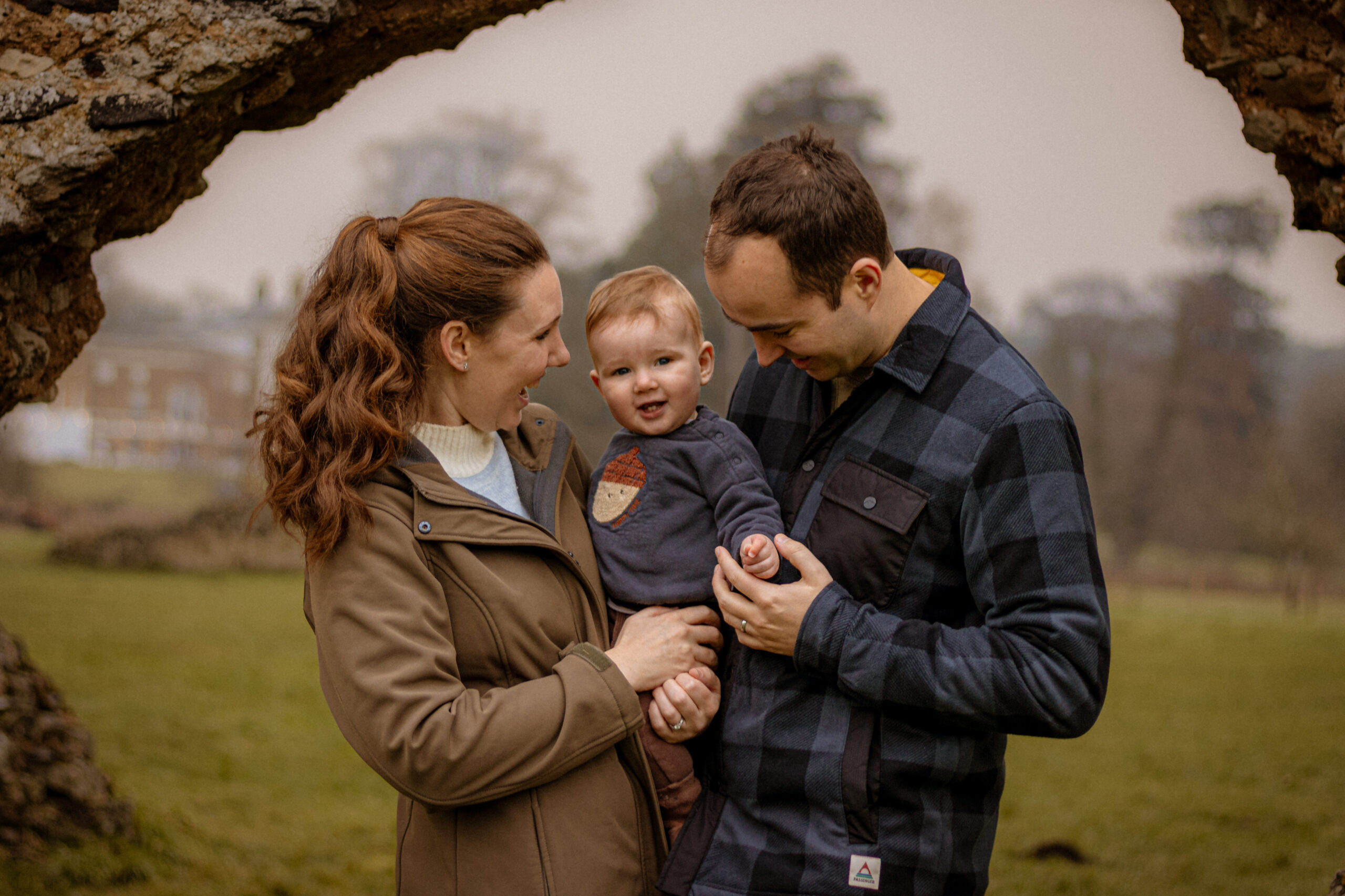 Relaxed autumn family photoshoot: Parents with baby in outdoor portrait.