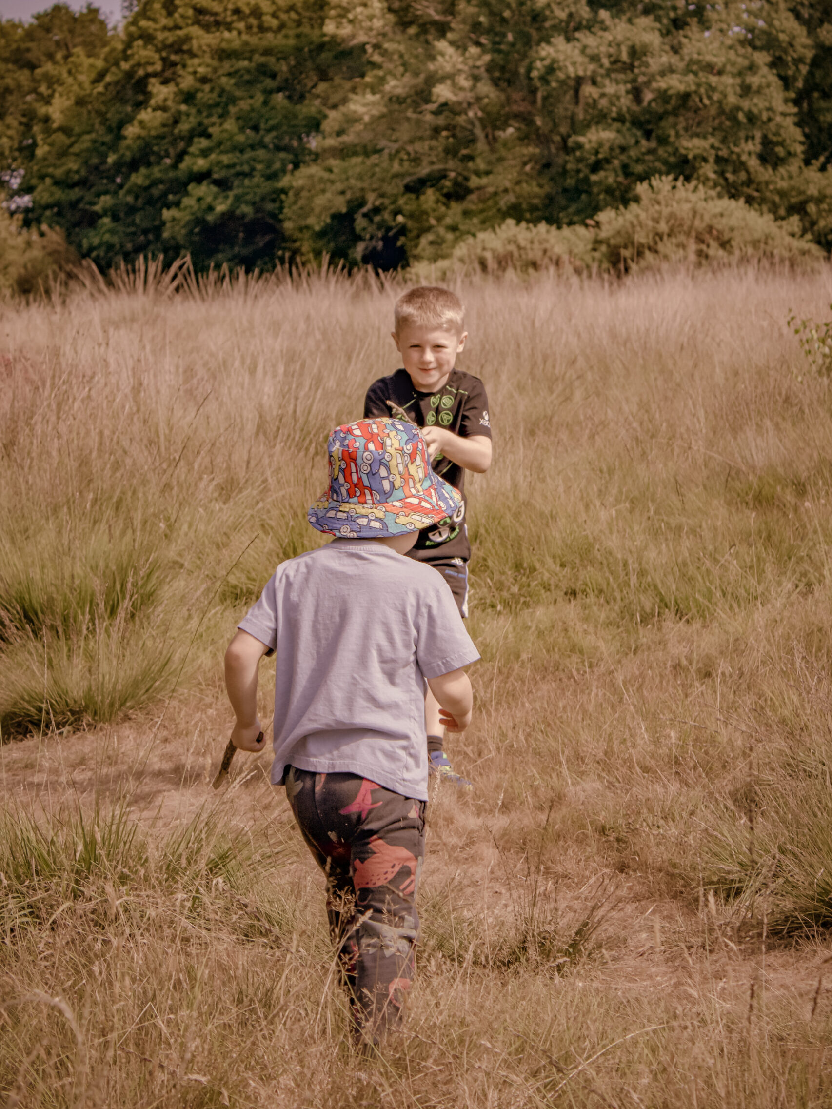 Children playing outdoors in a grassy field. Two boys enjoy nature and outdoor fun.