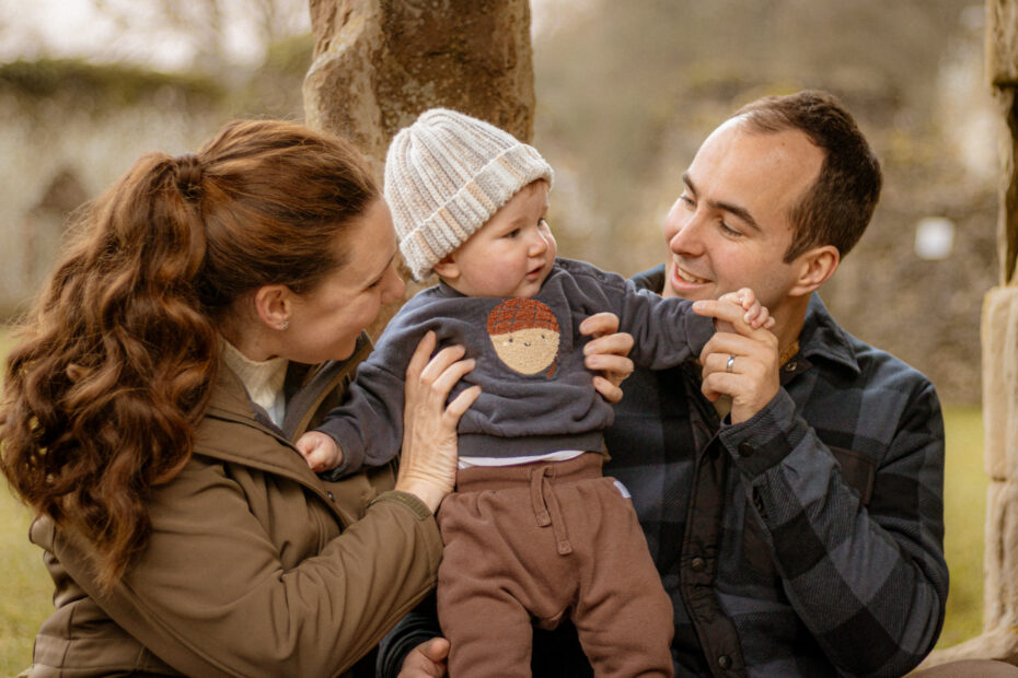 Natural family portrait in Petersfield. Mother, father, and baby share a loving moment. Outdoor photography, Monnington location.